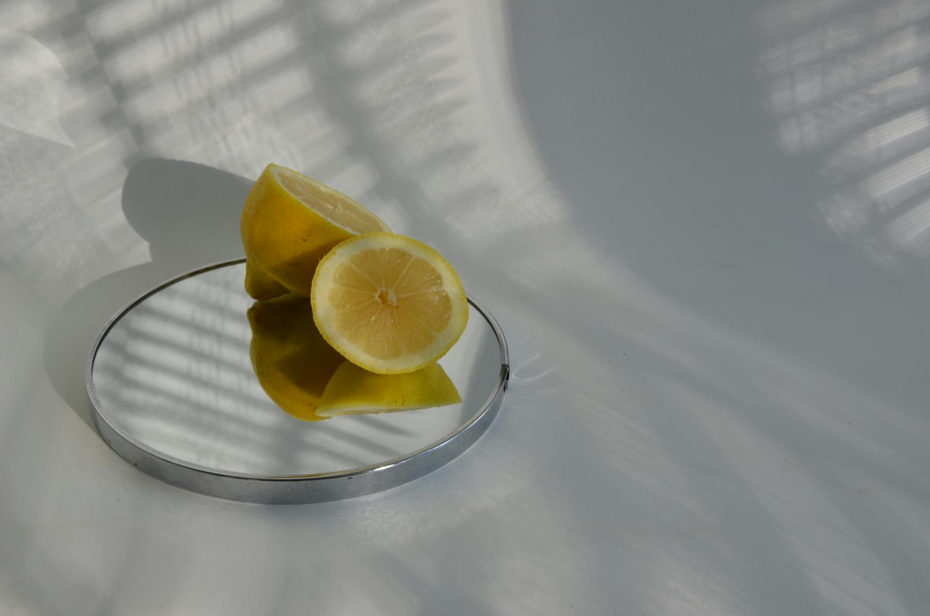 Limoni tagliati su uno specchio che proiettano ombre, che mostrano la fotografia minimalista del cibo