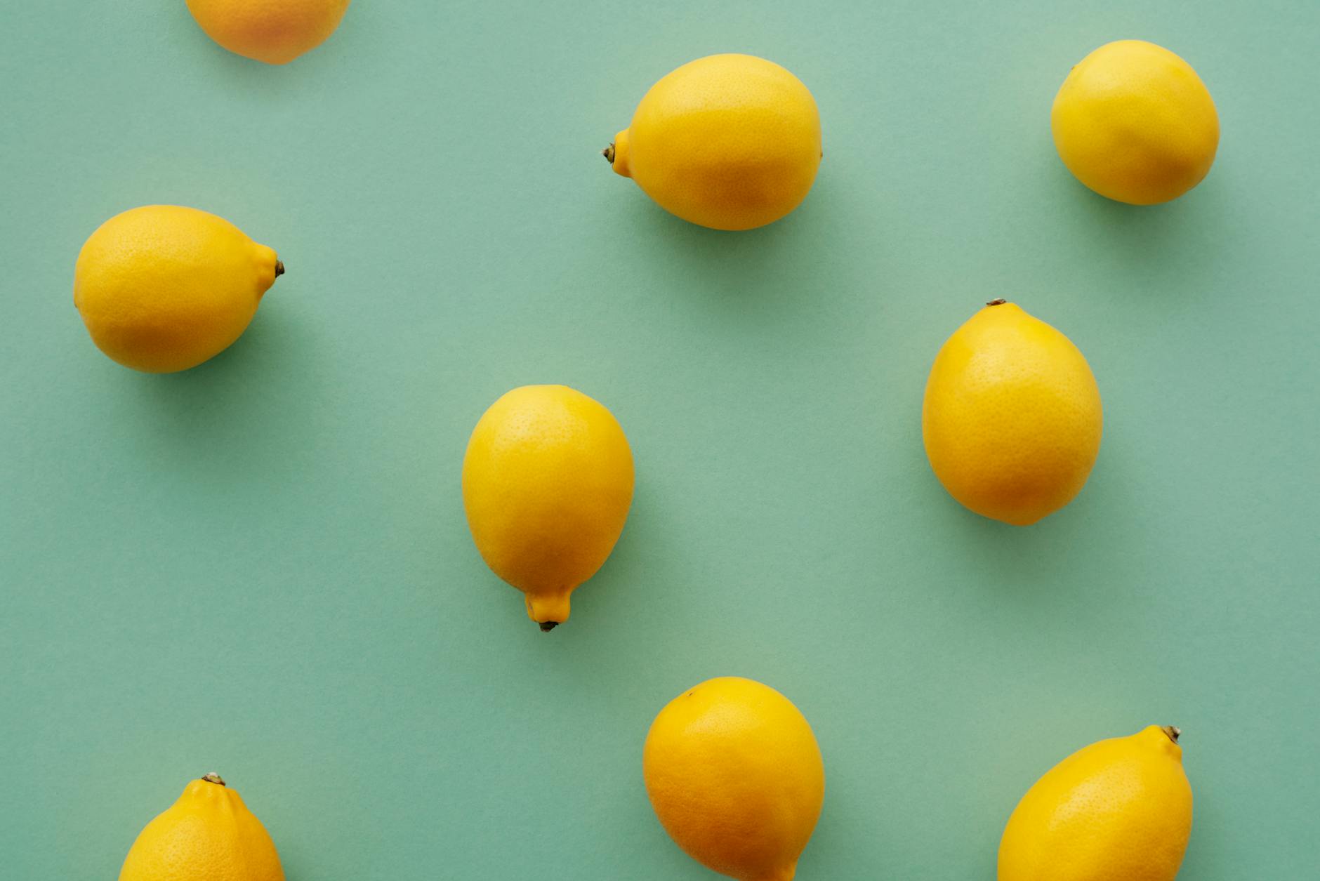 Bright yellow lemons arranged on a pastel green background, representing freshness and vitality through aging