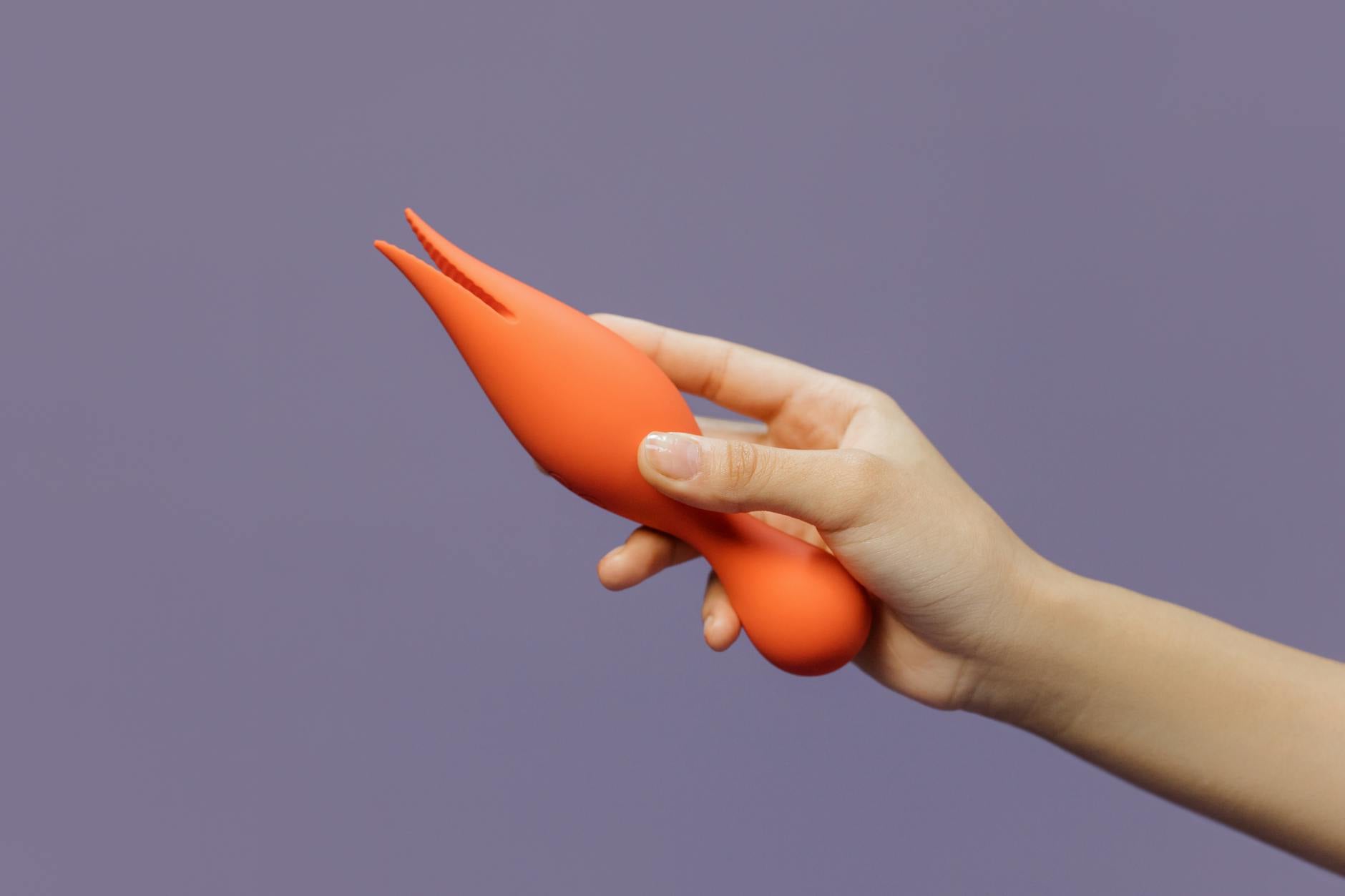 Donna che tiene in mano un vibratore arancione su sfondo viola minimalista