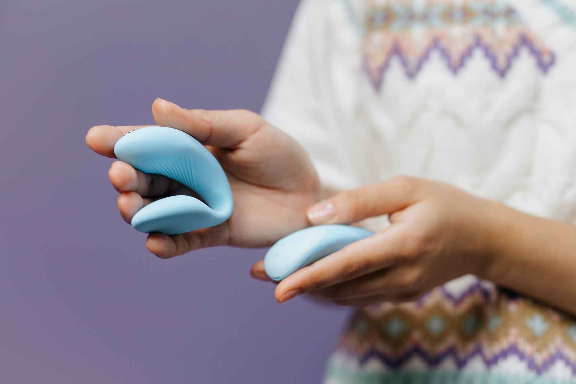 Two hands holding a sleek blue vibrator, symbolizing intimacy and reconnection between partners