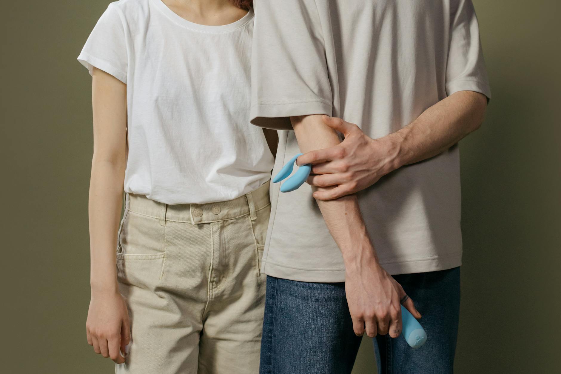 A young couple standing together indoors, exploring intimacy with modern toys.