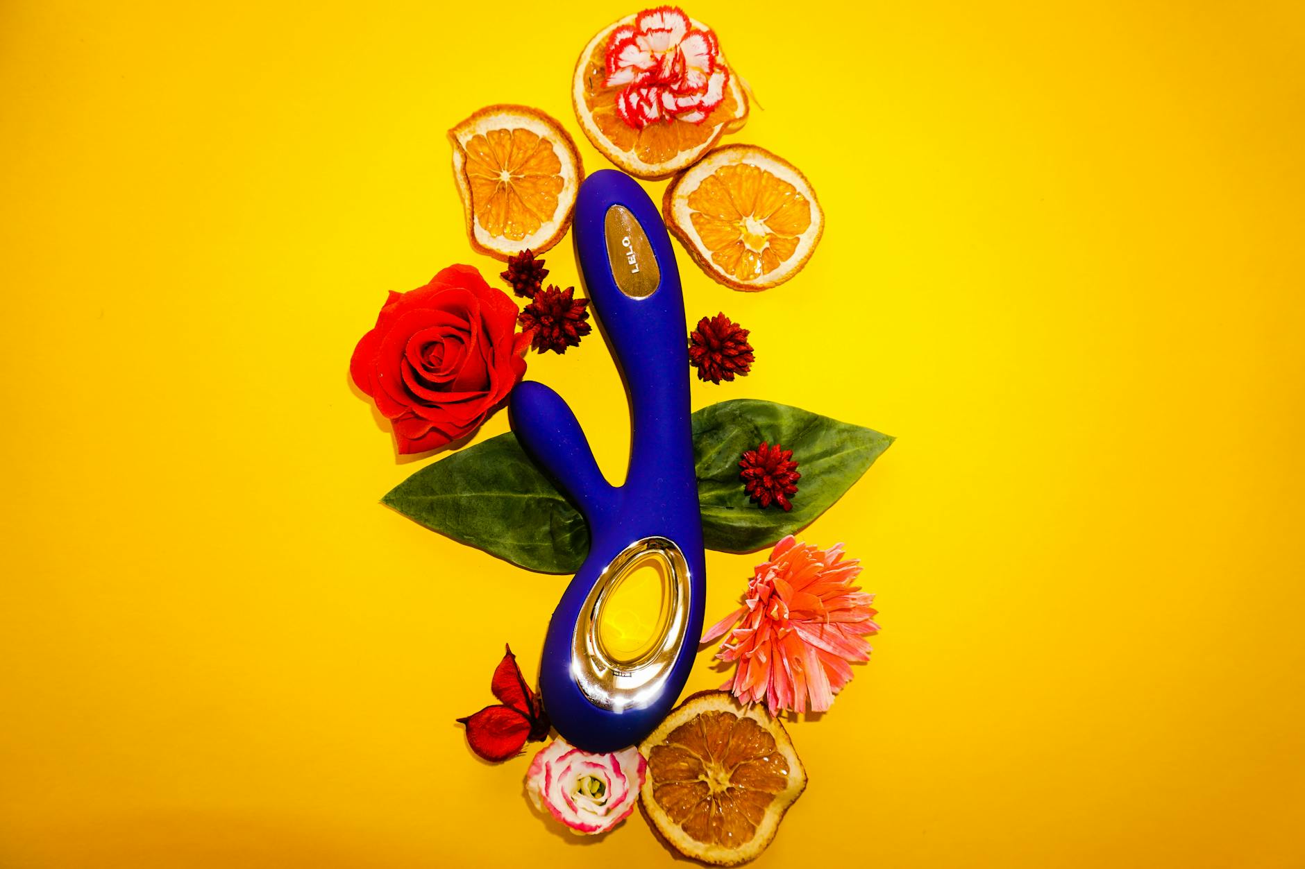 Hand holding an orange vibrator against a minimalistic purple backdrop, showcasing modern sensuality and openness